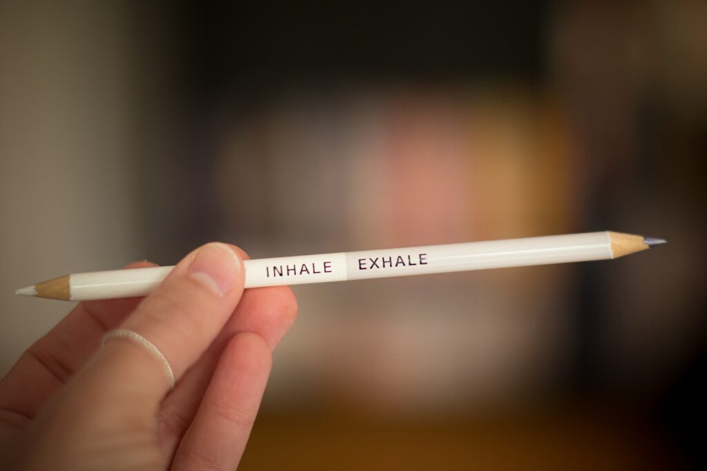 Hand hält Stift mit Auschrift Inhale Exhale