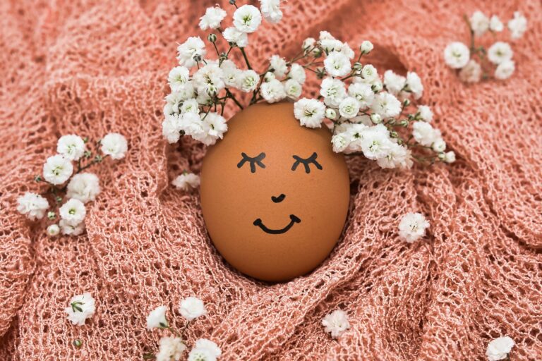Ei mit lächelndem Gesicht eingebettet in ein Tuch mit zierlichen Blumen