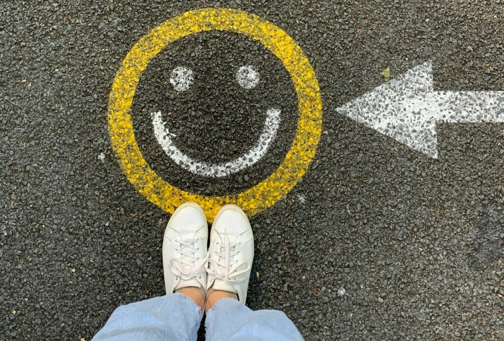 Füße stehen auf einem Smiley mit Pfeil